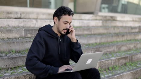 Man-using-laptop-and-talking-by-smartphone